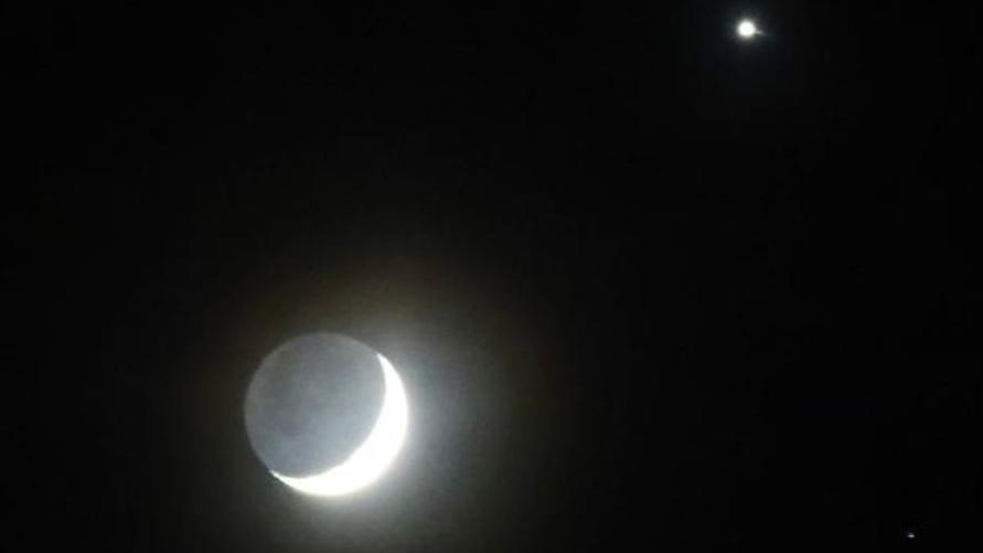 A crescent moon and Venus against a dark sky.