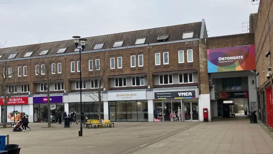 Ortongate shopping centre in Orton - a pedestrianised square with shopping units on the ground floor of three-storey terraced houses.