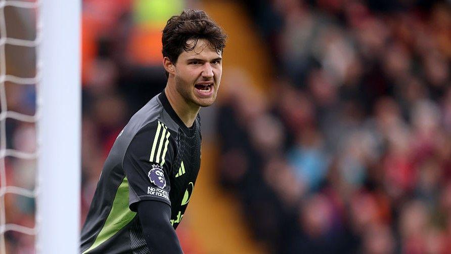 Senne Lammens, wearing Manchester United's dark-coloured goalkeeper top, shouts at his defenders during the game against Liverpool