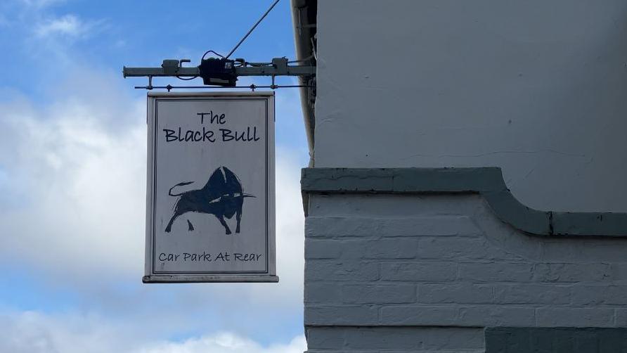 A zoomed in view of the Black Bull pub sign, it features black bull in a defensive stance.