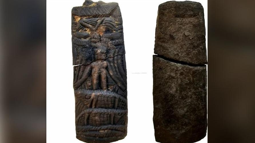 Both the front and back of the amulet can be seen, with an image of the god Harpocrates standing on top of two crocodiles with the head of the god Bes above him carved into it. The back does not appear to have anything carved into it.