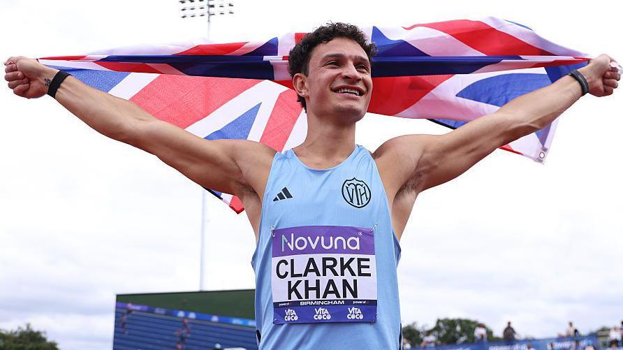 High jumper Joel Clarke-Khan holds the Union Flag above his head after winning the UK title