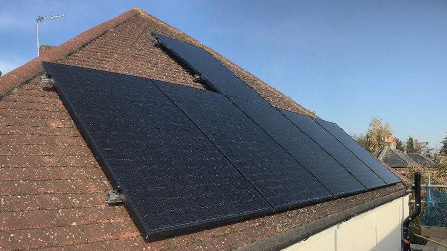 Six solar panels on a brown roof. The solar panels are a dark black/blue colour.