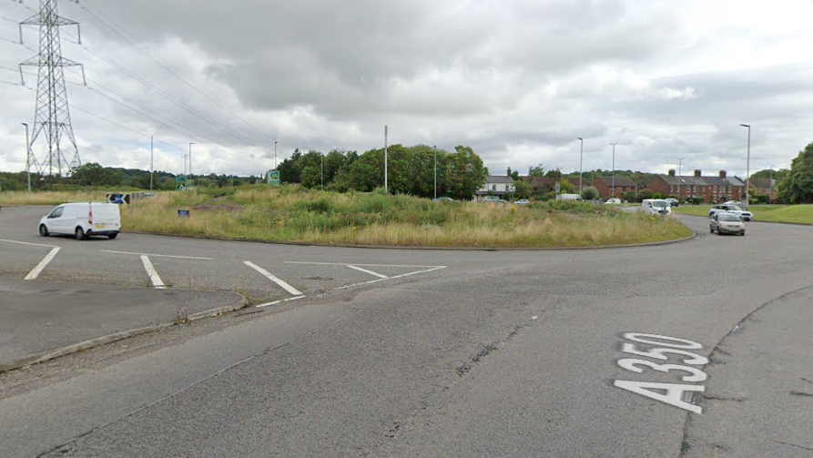 The Bumpers farm roundabout in Chippenham. It has a grassy area in the middle, with residential properties in the background. 