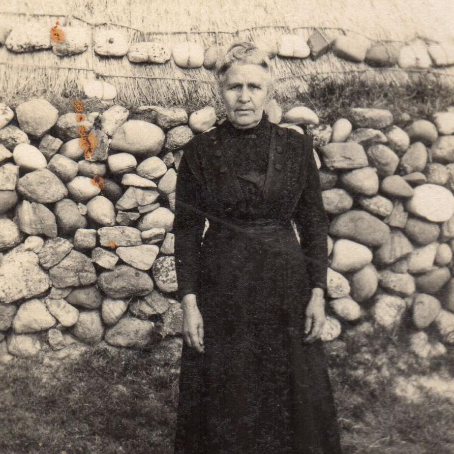 A woman standing by a stone wall