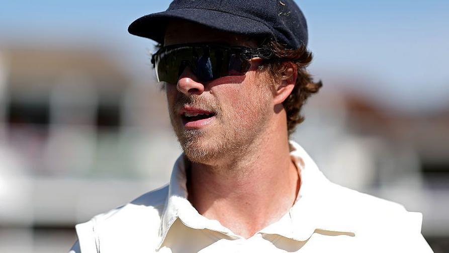 Sam Northeast stands in the outfield last season for Glamorgan wearing a cap and pair of shades