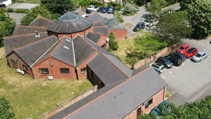 Aerial view of Langport Surgery on the A378 North Street In Langport. It is a jagged circular brick building with a central dome and smaller buildings coming off the middle