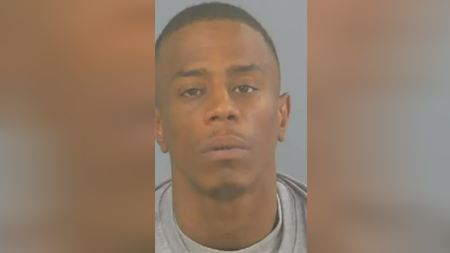 A mugshot of Donovan Thomas, who is wearing a grey sweatshirt and grey T-shirt 