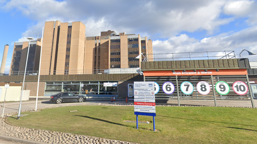 The main entrance to Raigmore with signage, including ones showing numbers and colours of different zones in the hospital. 