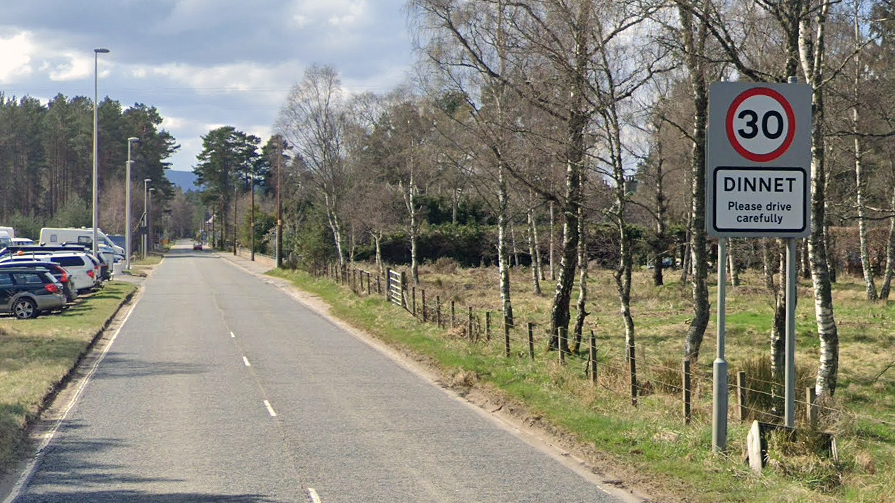 road into dinnet with street sign and trees