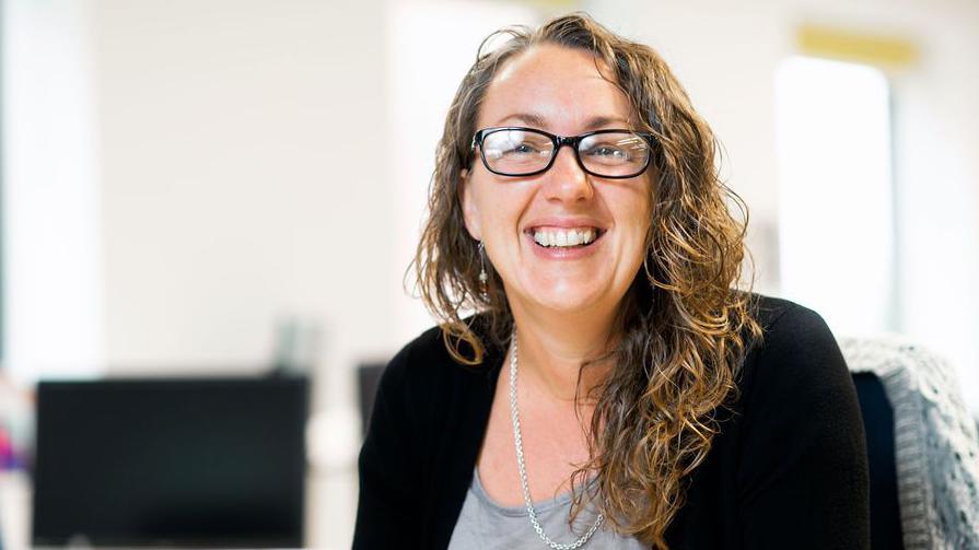 Jo Atkinson looking happy and sitting at her desk