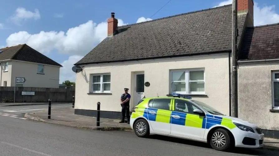 Plismon a cherbyd heddlu tu allan i gartref Lisa Fraser ar Military Road, Doc Penfro