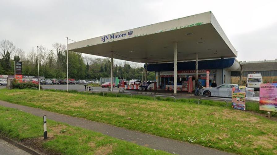 A wide shot of a car dealership with several cars on the forecourt