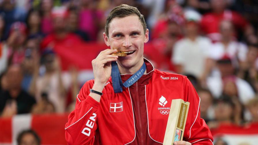 Viktor Axelsen bites his Olympic gold medal