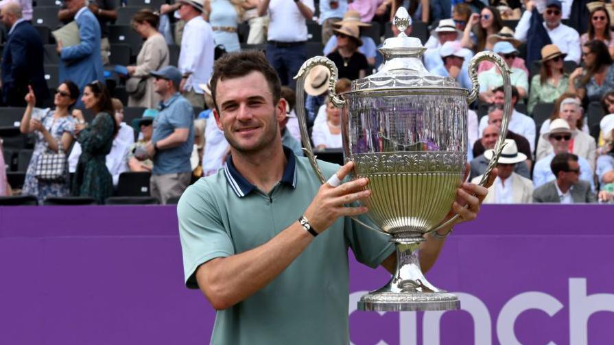 Tommy Paul holds the trophy as he celebrates winning the men's singles event at Queen's in 2024