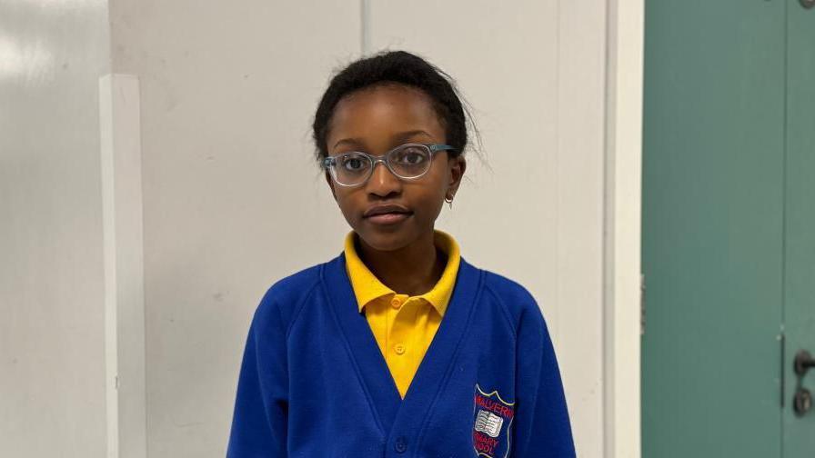 Little girl wearing yellow polo top and blue school uniform cardigan