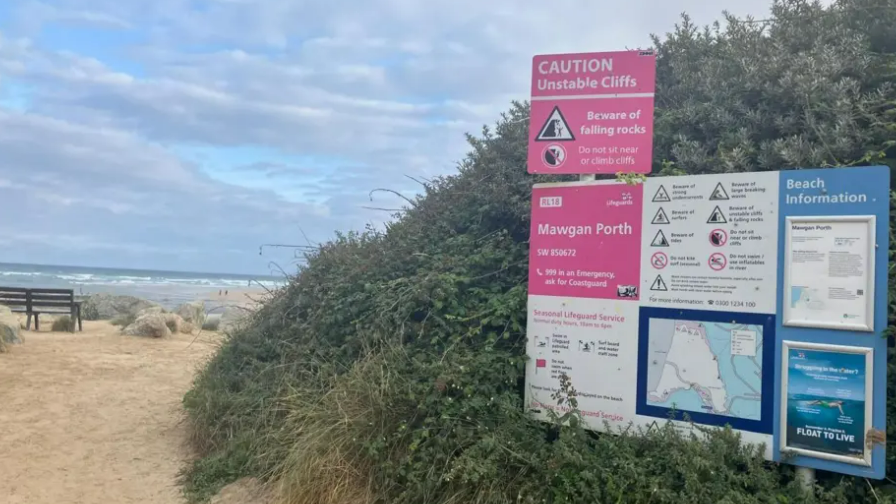 Entrance to the beach. Beach safety signs are on display at the entrance.