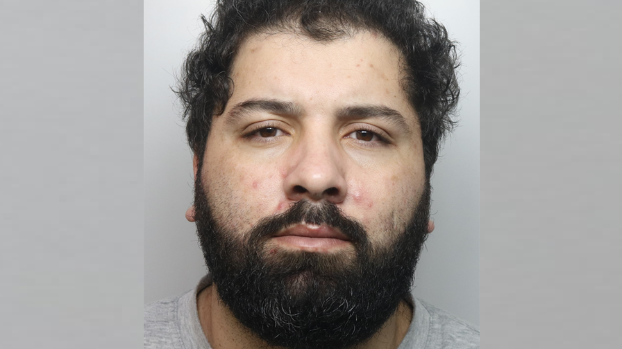 A police custody photo shows Walid Sadaoui with a full, dark beard and curly, dark hair. He wears a light-grey, collarless top.