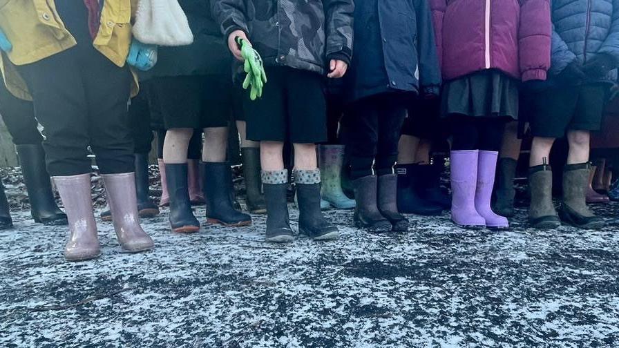 Children's feet in wellies of various colours, on a frosty pavement