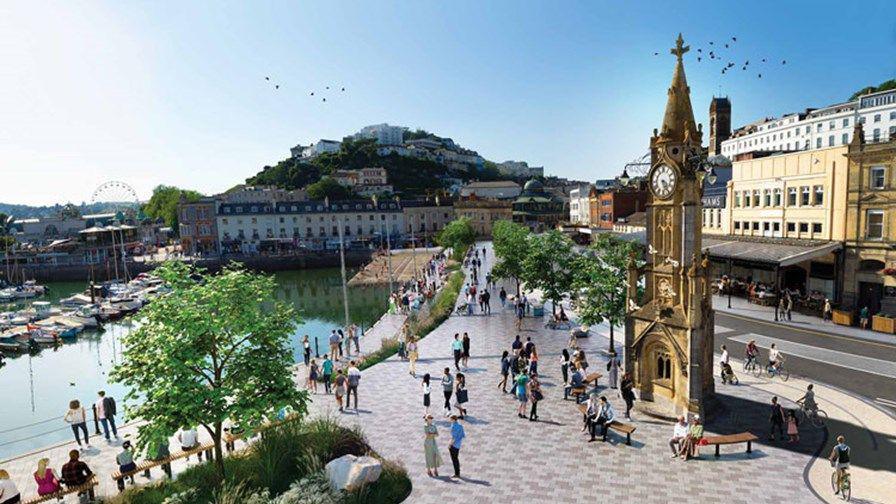 An artist's impression showing the Strand in Torquay. People are walking along the harbourside around a clock tower. Next to them is a road and shops.