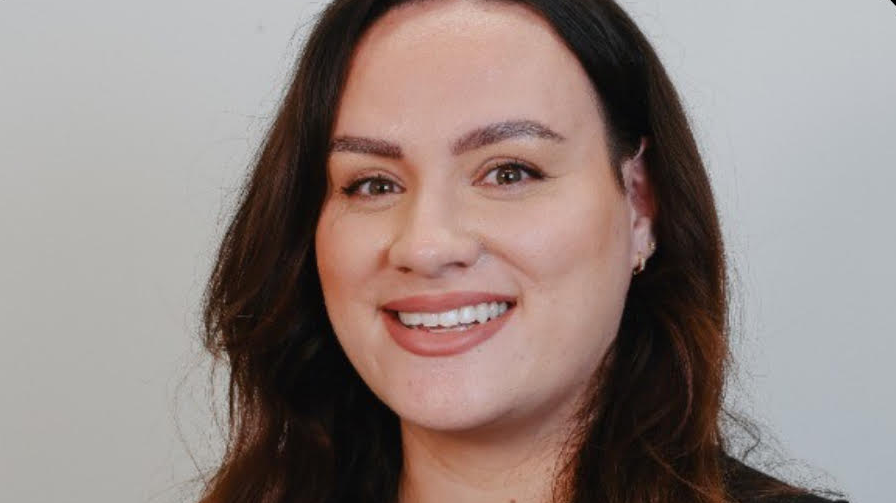 Chantel smiles into the camera in a professional photo. She has brown eyes and hair and gold earrings. 