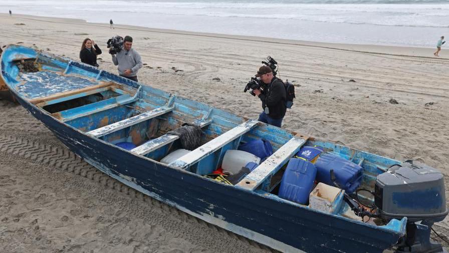 Members of the media photograph the small boat that capsized off Torrey Pines State Beach