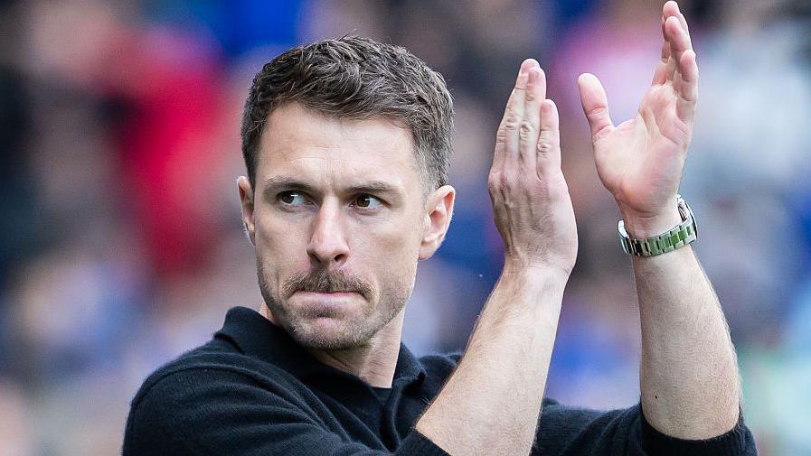 Aaron Ramsey in dark sweater applauds
