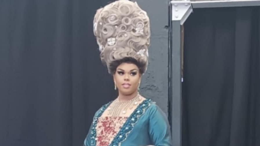 A black man in a blue dress with an ornate period-style white wig