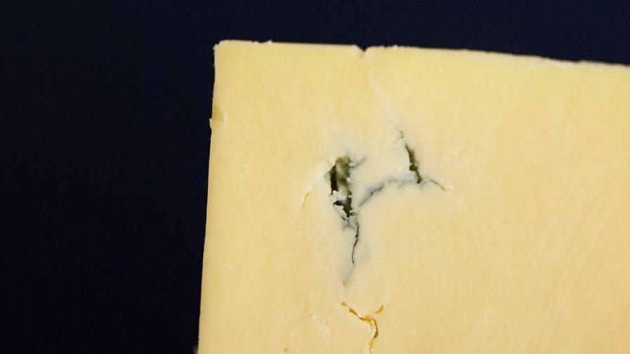 Close-up of yellow cheese with a little crack in it. 