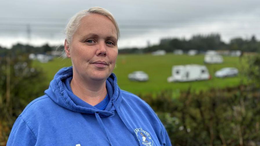 Volunteer and parent Jemma Marriot overlooking the football pitches with caravans in the background taking up space on the field.