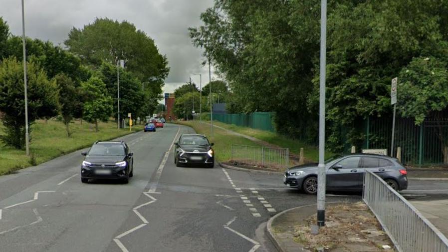 Google Streetview photograph of two unidentified black cars travelling along Childwall Valley Road. One of them is indicating to turn left at a T-junction. Another black car is waiting to join the main road from Chislehurst Avenue.