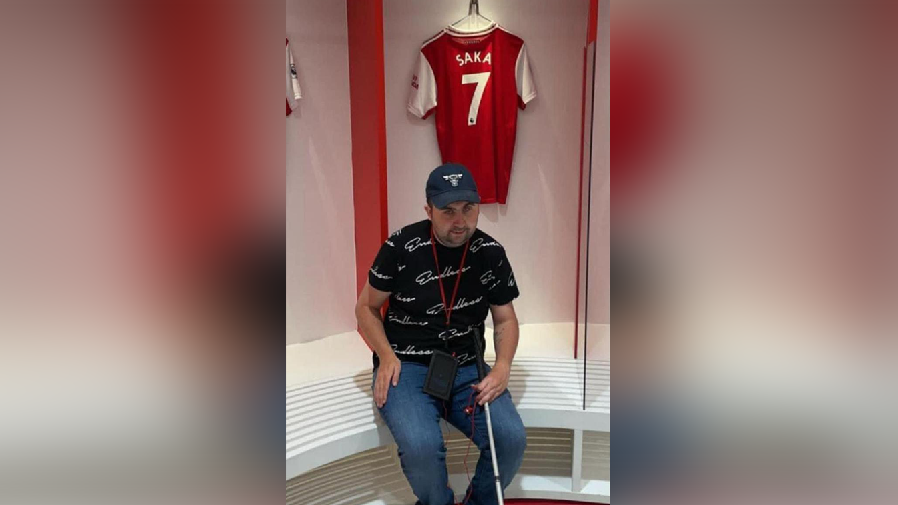 Mr Sullivan with his Bukayo Saka shirt, sitting in the Arsenal dressing room