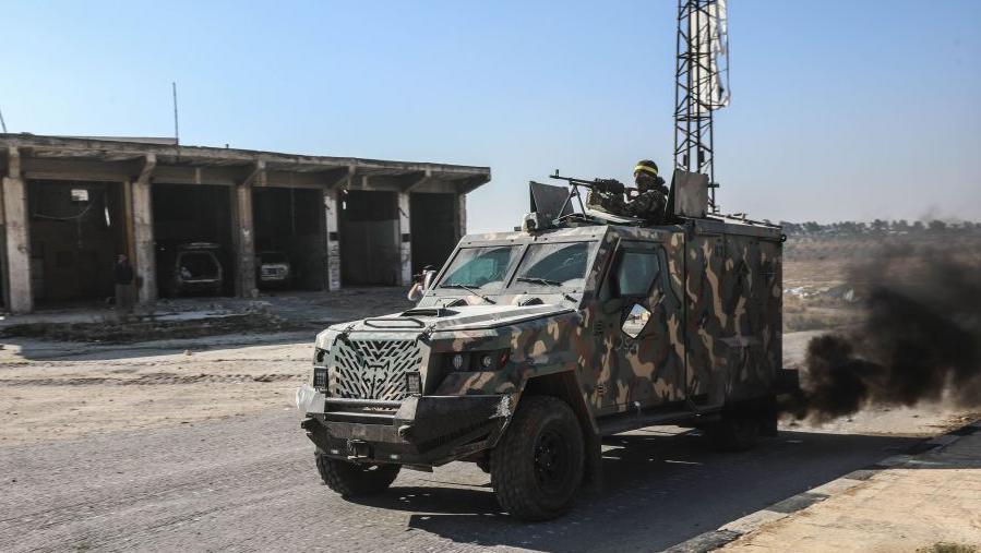 Rebel fighters led by Hayat Tahrir al-Sham (HTS) drive an armoured vehicle during an offensive against government forces in north-western Syria (28 November 2024)