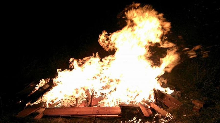 A bonfire, with orange wood and brown flames, in a shape similar to Guernsey. 