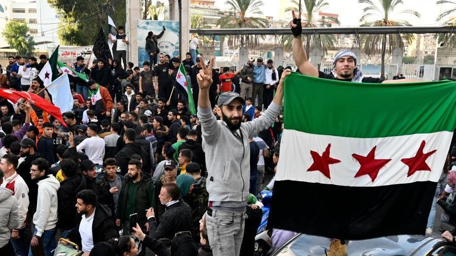 Crowds of people waving flags in Damascus after the fall of the Assad regime in Syria.