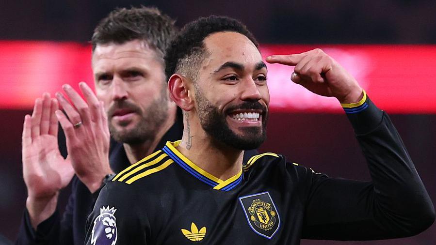 Matheus Cunha points to his head with Michael Carrick applauding behind him