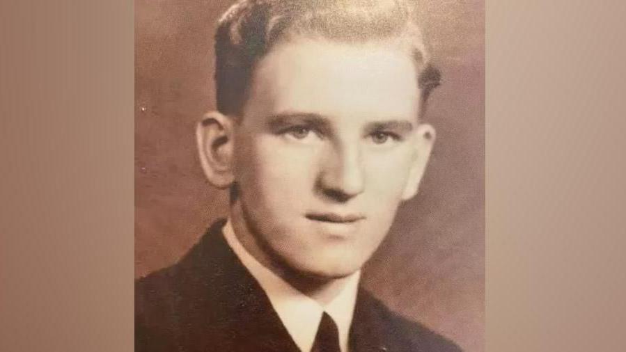 A black and white image of a very young William Wake. He is clean shaven, 18 years old and wearing a black jacket and tie.