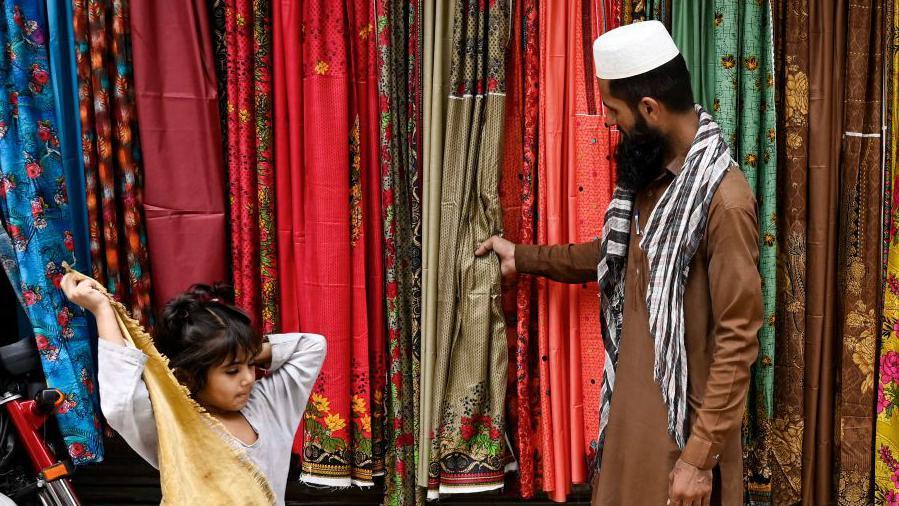 A shopkeeper and a child at aroadside shop in Lahore, Pakistan.