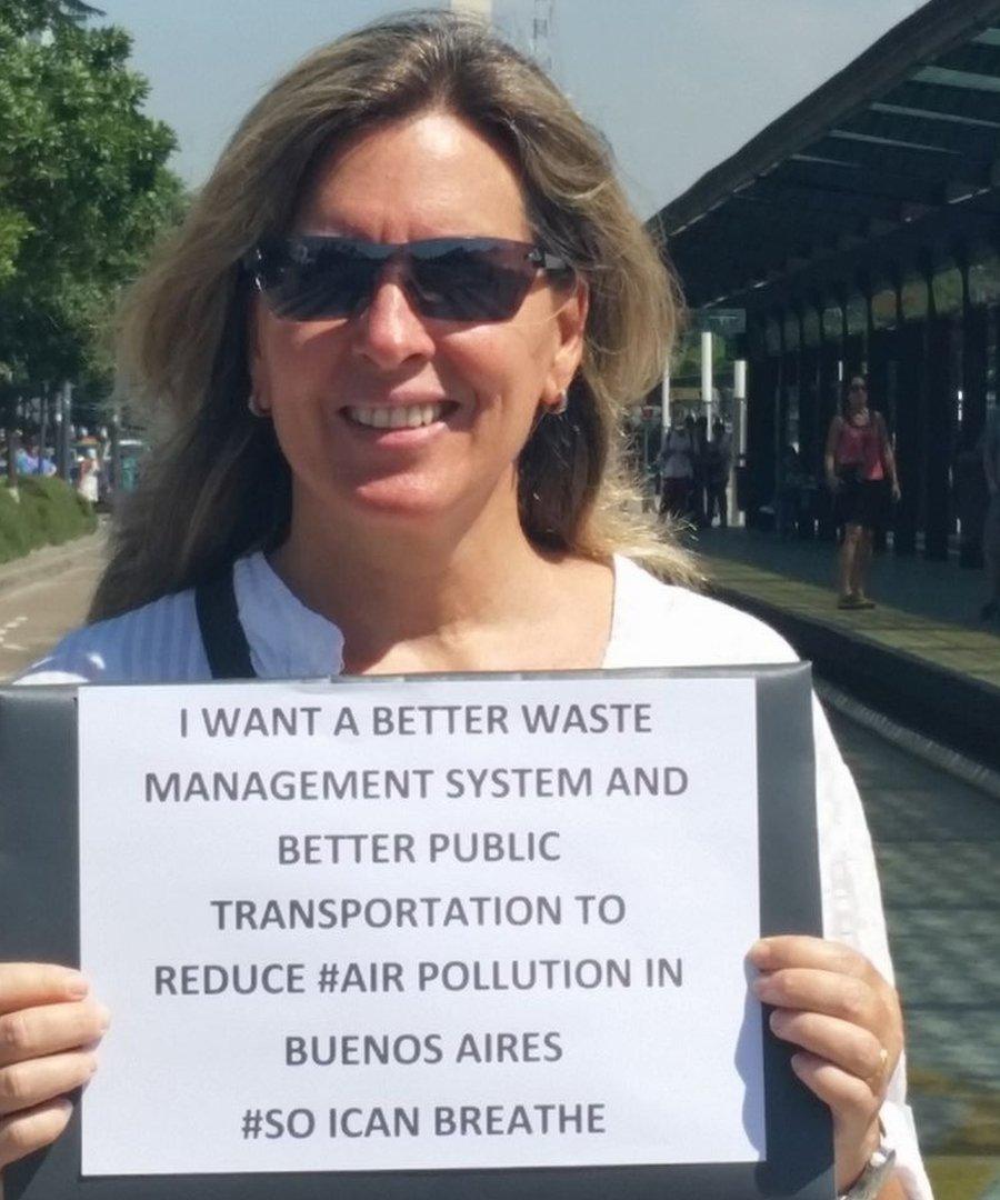 Maria Innes in Buenos Aires holding a sign: I want a better waste management system and better public transportation to reduce #AirPollution in Buenos Aires #SoICanBreathe