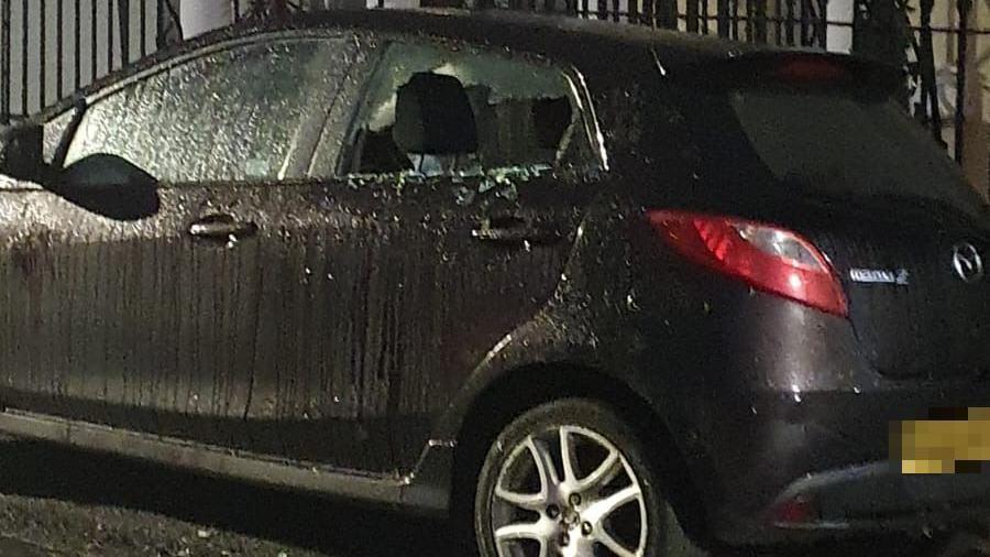 A black Mazda car with a smashed rear passenger window