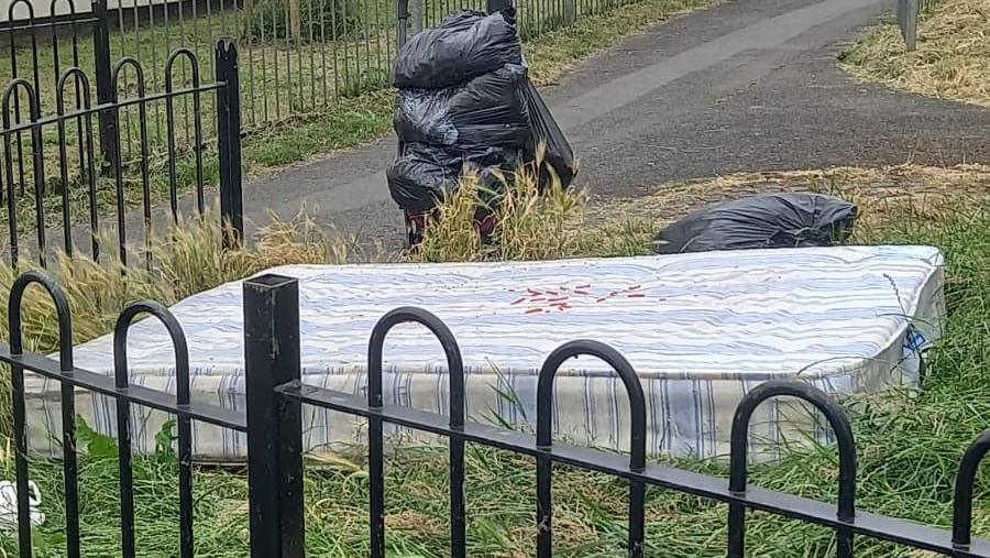 Old mattress dumped on a grassed area in a city street