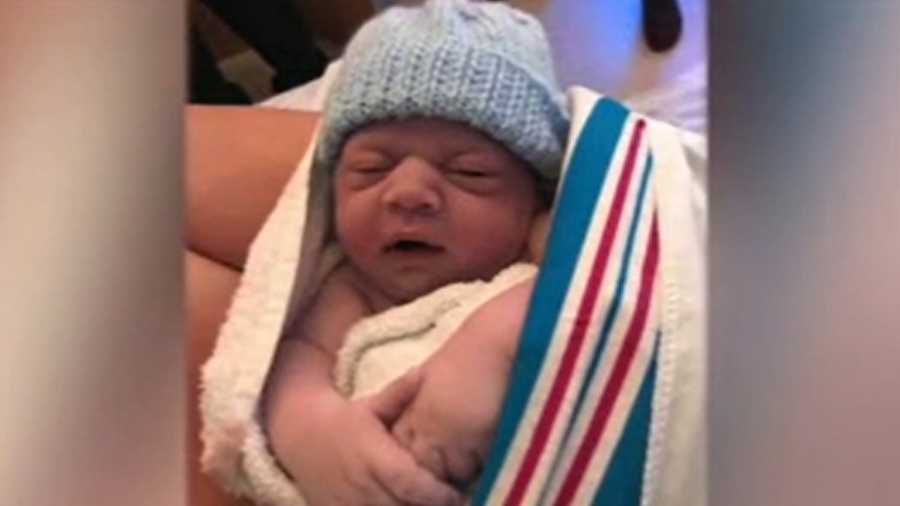 An image of a baby in a blue knitted hat wrapped in a blanket. 