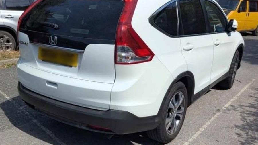 A white car parked in a faded white parking space.