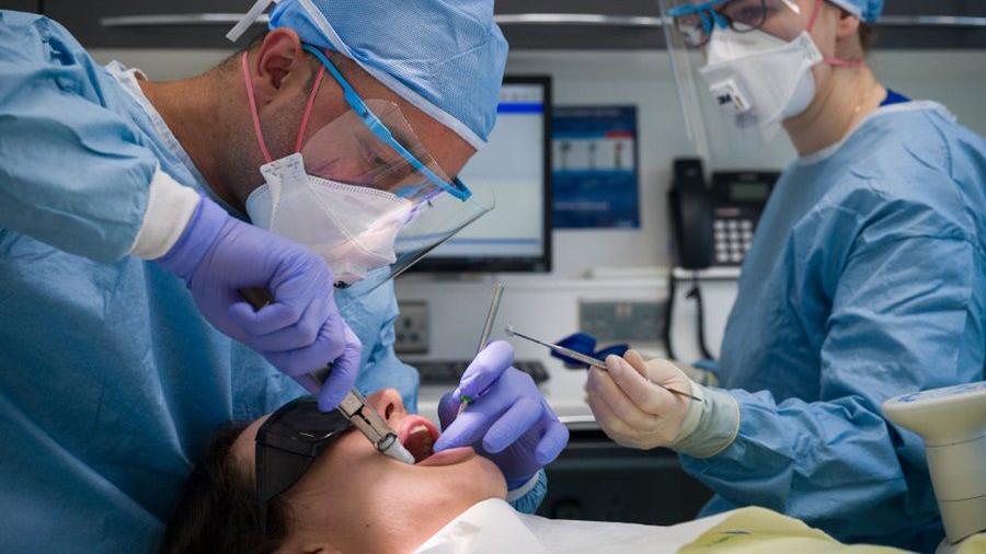 Two dentists treating a patient.