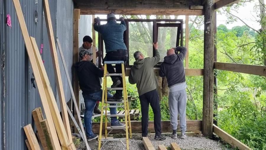 Volunteers putting in windows into the wooden framework of Belper Shed