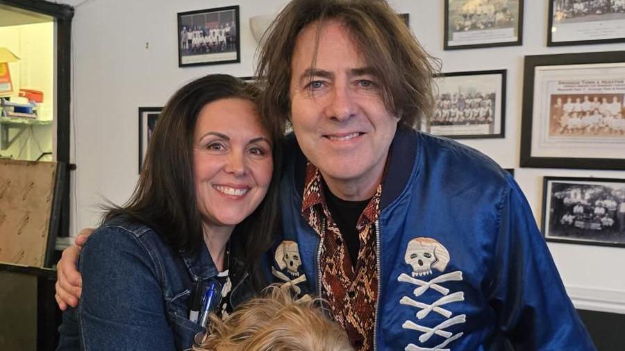 Sabrina Ramsey stood next to Jonathan Ross. She is holding one of Jonathan's dogs in her arms.