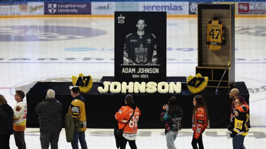 A podium with a picture of Adam Johnson next to his 47 jersey - on the ice of an ice rink 