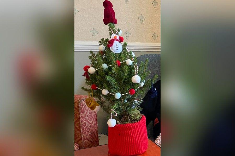 A small potted Christmas tree is decorated with a variety of red and white decorations, including a snowman.