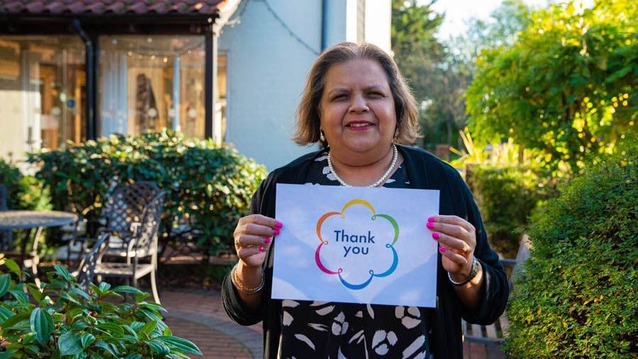 Sushma Dhami holding up a poster that says Thank you