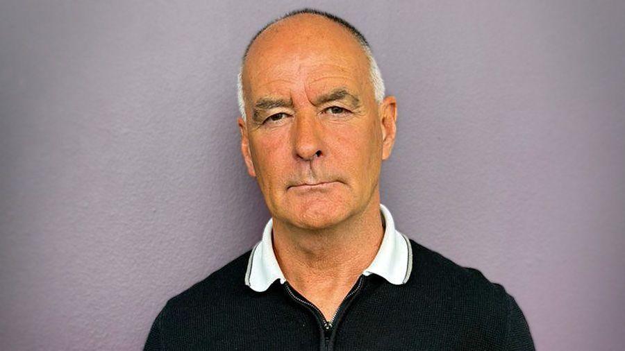 Tommy Sherdian head and shoulder shot in a black top with white collar